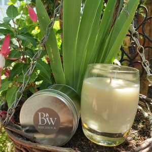 Curved glass candle and tin candle, set against a natural background..